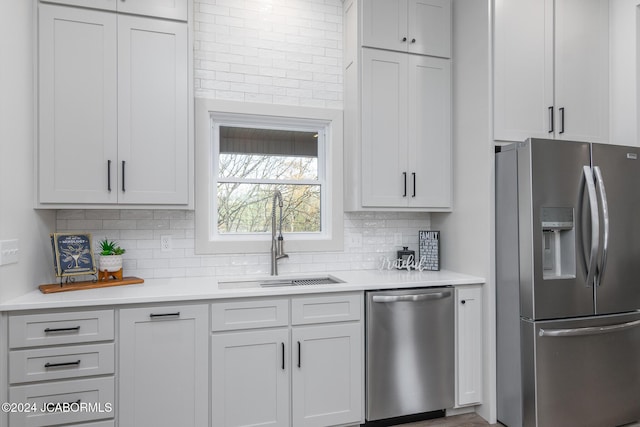 kitchen featuring backsplash, white cabinetry, sink, and appliances with stainless steel finishes