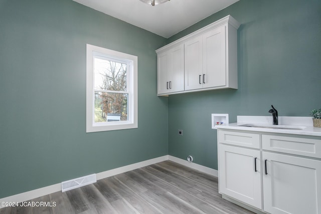 laundry room featuring cabinets, washer hookup, hookup for an electric dryer, sink, and light hardwood / wood-style floors