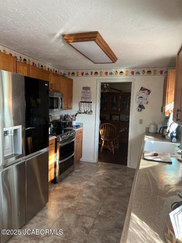 200 Sondra Ave, Columbia, MO 65202 - kitchen with brown cabinetry, light countertops, stainless steel appliances, and a textured ceiling