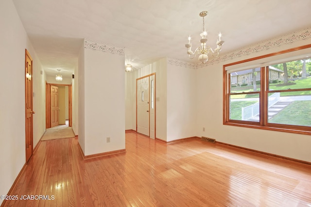 1101 E Maplewood Ct, Jefferson City, MO 65109 - unfurnished room featuring a chandelier, light wood-style floors, and baseboards