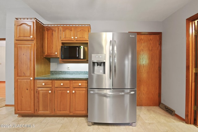 1101 E Maplewood Ct, Jefferson City, MO 65109 - kitchen featuring stainless steel fridge, dark countertops, brown cabinetry, light tile patterned floors, and baseboards