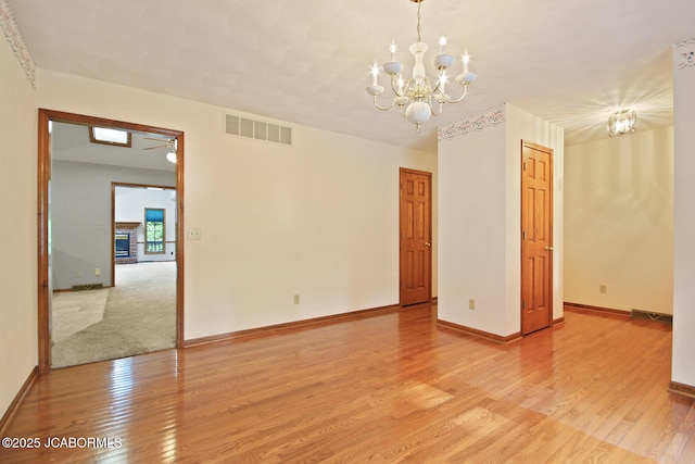 1101 E Maplewood Ct, Jefferson City, MO 65109 - empty room featuring a chandelier, light wood finished floors, baseboards, and ceiling fan