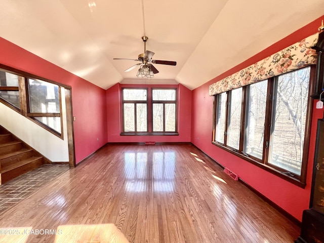 unfurnished living room featuring lofted ceiling, hardwood / wood-style flooring, stairway, and baseboards