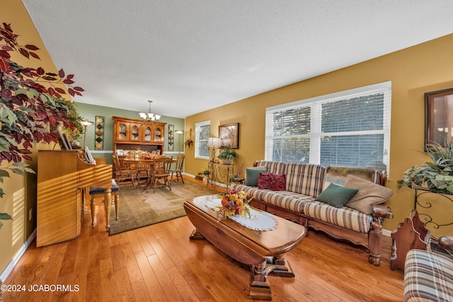 living room with a textured ceiling, light hardwood / wood-style floors, and an inviting chandelier