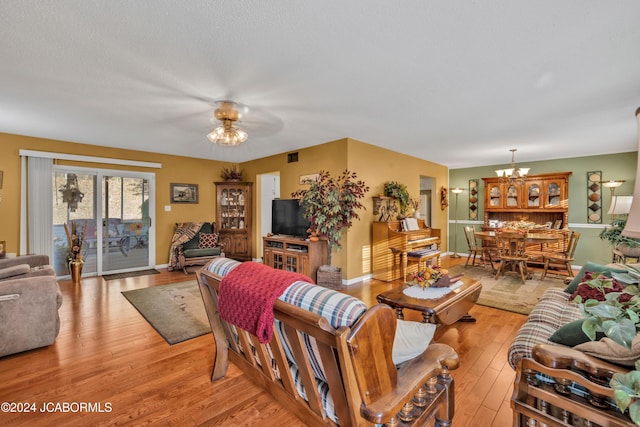 living room with light hardwood / wood-style floors and ceiling fan with notable chandelier