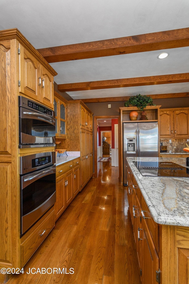 kitchen with backsplash, dark hardwood / wood-style floors, light stone countertops, appliances with stainless steel finishes, and beam ceiling