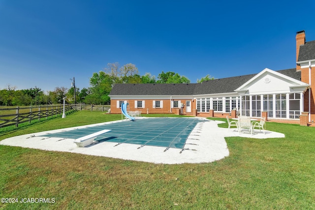 exterior space featuring a water slide, a diving board, a patio area, and a lawn