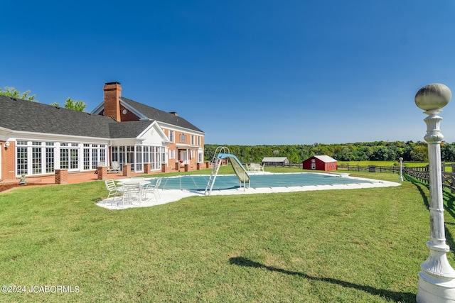 view of pool with a lawn and a storage unit