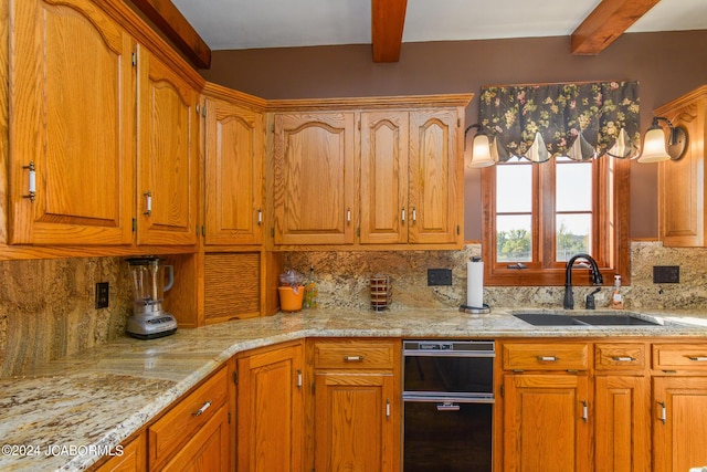 kitchen with decorative backsplash, beam ceiling, light stone counters, and sink