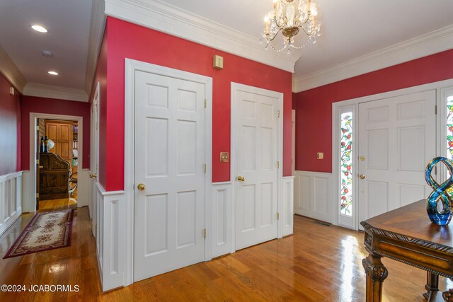 foyer entrance featuring crown molding, hardwood / wood-style flooring, and a notable chandelier