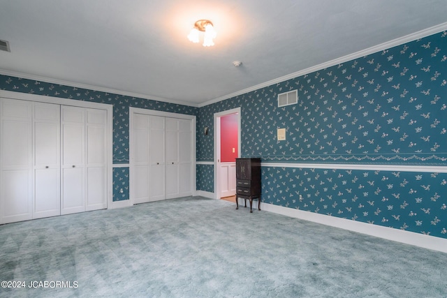 unfurnished bedroom with carpet flooring, crown molding, and multiple closets