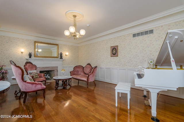 sitting room with hardwood / wood-style floors, crown molding, and a notable chandelier