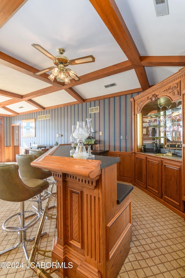 kitchen featuring light carpet, coffered ceiling, ceiling fan, beamed ceiling, and a center island