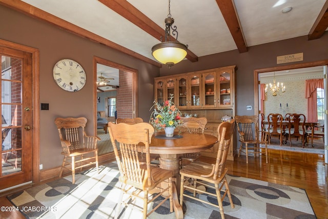 dining area featuring a wealth of natural light, beamed ceiling, ceiling fan with notable chandelier, and light wood-type flooring