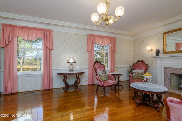 sitting room with wood-type flooring, a premium fireplace, a wealth of natural light, and a chandelier