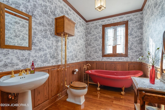 bathroom featuring a tub to relax in, hardwood / wood-style flooring, toilet, and crown molding