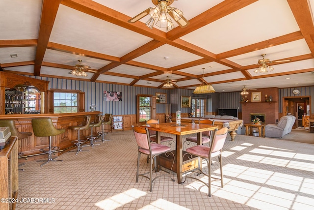 carpeted dining room featuring beam ceiling, indoor bar, a brick fireplace, and coffered ceiling