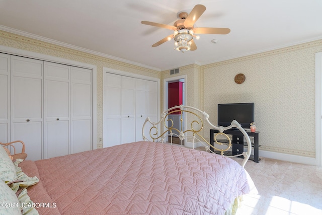 bedroom featuring ceiling fan, crown molding, and two closets