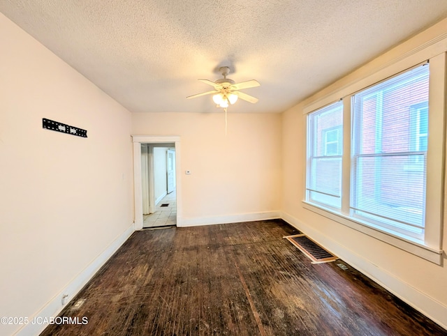 empty room with dark wood-type flooring, ceiling fan, and a textured ceiling