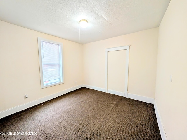 carpeted empty room featuring a textured ceiling