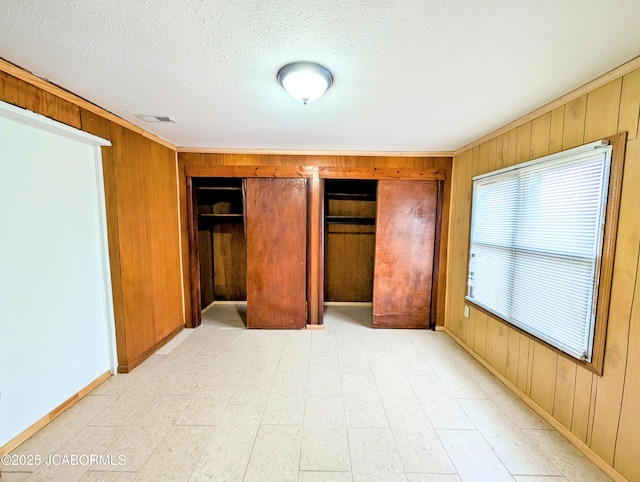 unfurnished bedroom with wooden walls and a textured ceiling