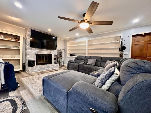 living room featuring crown molding, a brick fireplace, ceiling fan, built in features, and light hardwood / wood-style floors