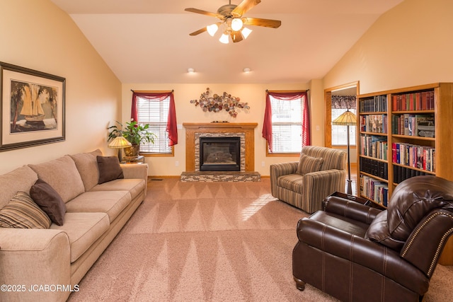 living room with lofted ceiling, carpet, a ceiling fan, and a stone fireplace