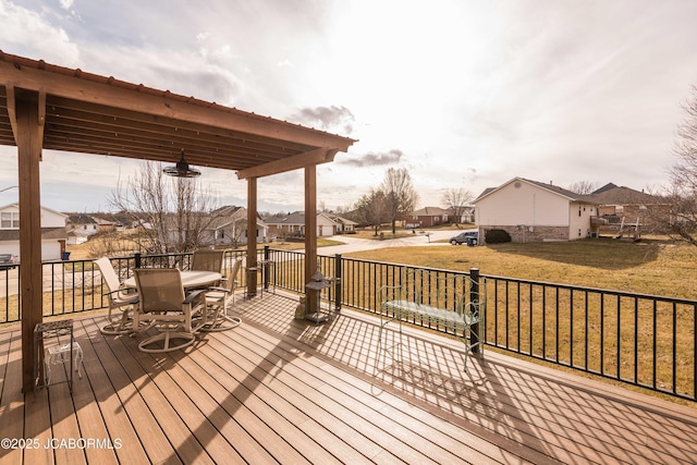 wooden terrace with a residential view, outdoor dining area, and a yard