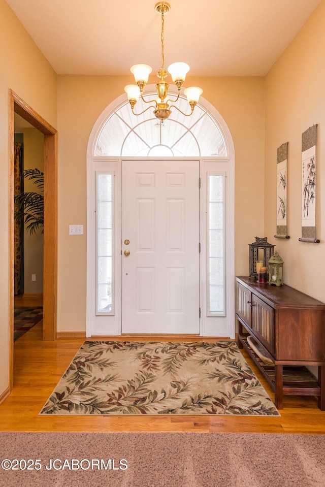 entryway with a wealth of natural light, a notable chandelier, and wood finished floors