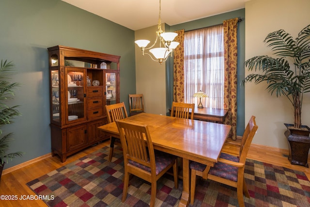 dining area featuring an inviting chandelier, wood finished floors, and baseboards