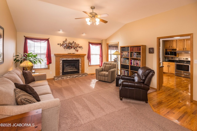 living area featuring lofted ceiling, carpet, a glass covered fireplace, and a wealth of natural light