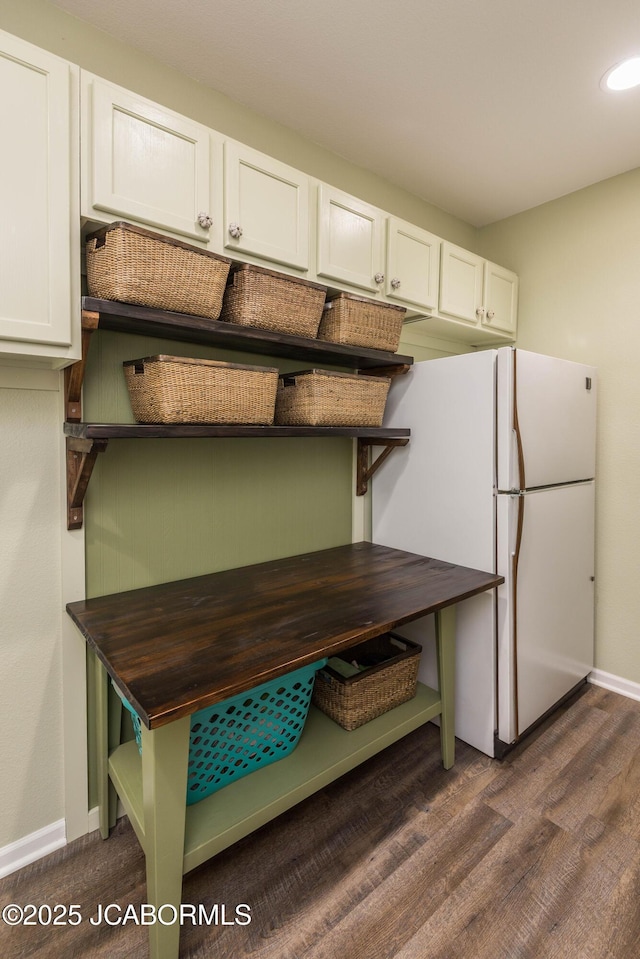 kitchen featuring dark wood-style floors, baseboards, white cabinets, and freestanding refrigerator