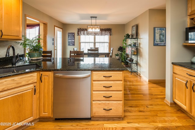 kitchen featuring dark stone counters, a sink, light wood-type flooring, dishwasher, and a peninsula