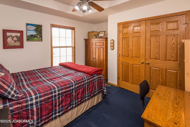 bedroom with ceiling fan, dark carpet, and a closet