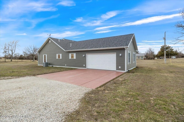 view of side of home featuring a shingled roof, a lawn, an attached garage, central AC, and driveway