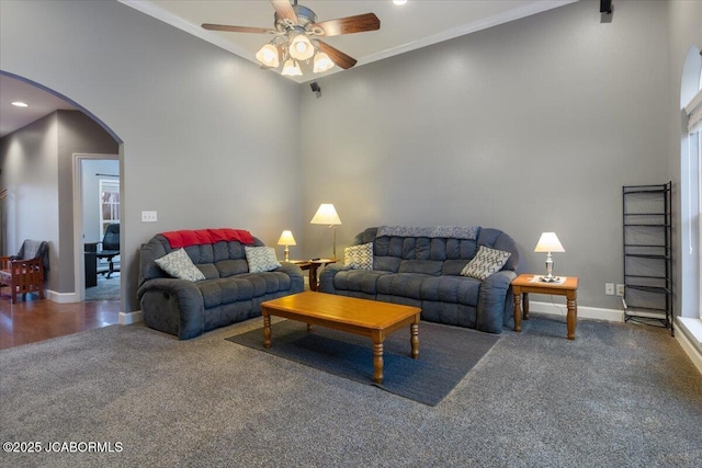 carpeted living area with a ceiling fan, arched walkways, crown molding, and baseboards