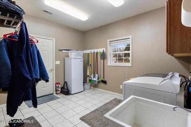 laundry room with cabinet space, light tile patterned floors, visible vents, separate washer and dryer, and a sink