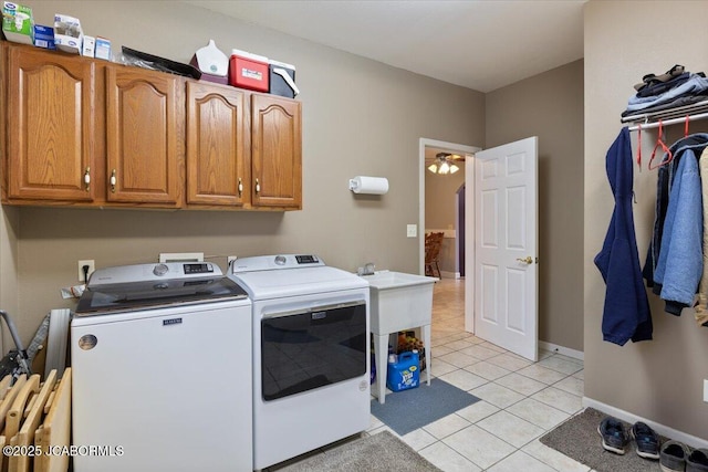 laundry area featuring light tile patterned floors, washing machine and dryer, cabinet space, and baseboards