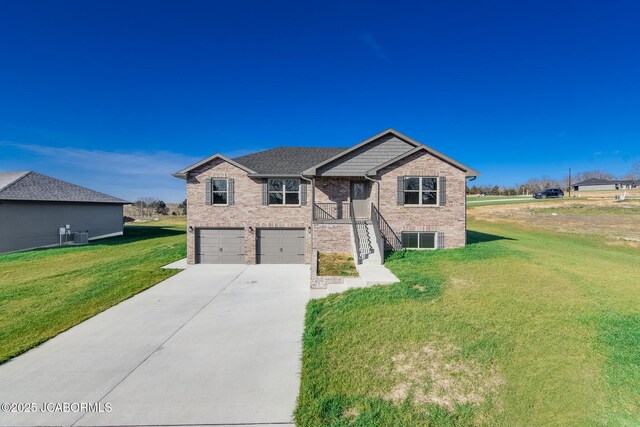 view of front of property with central air condition unit, a front lawn, and a garage