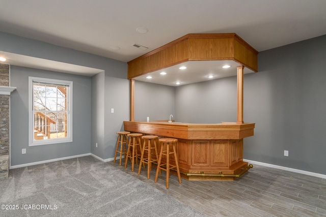 bar with visible vents, recessed lighting, bar area, and baseboards