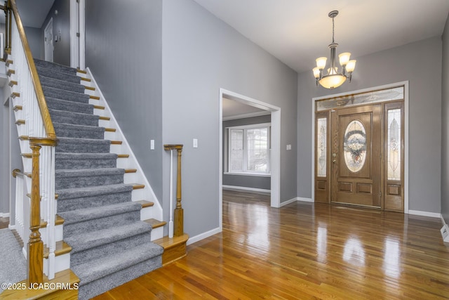 entryway with stairway, baseboards, wood finished floors, and a chandelier