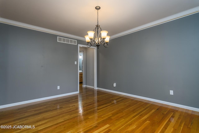 unfurnished room featuring visible vents, baseboards, ornamental molding, wood finished floors, and a notable chandelier