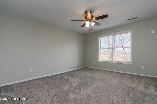 carpeted spare room with visible vents, baseboards, and a ceiling fan