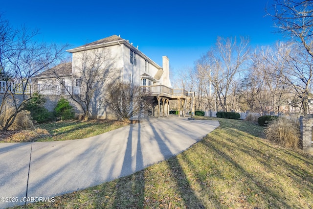 view of property exterior featuring stucco siding, a lawn, and stairs