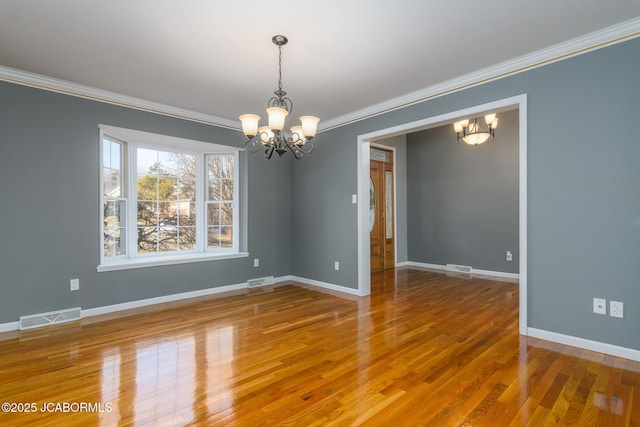 spare room featuring a notable chandelier, wood finished floors, and visible vents