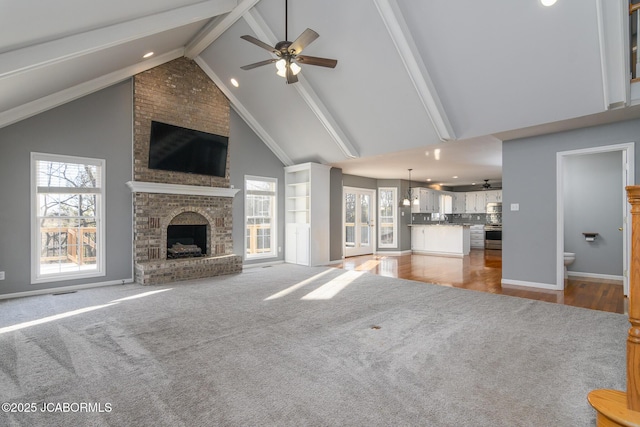 unfurnished living room with baseboards, beam ceiling, a fireplace, high vaulted ceiling, and a ceiling fan