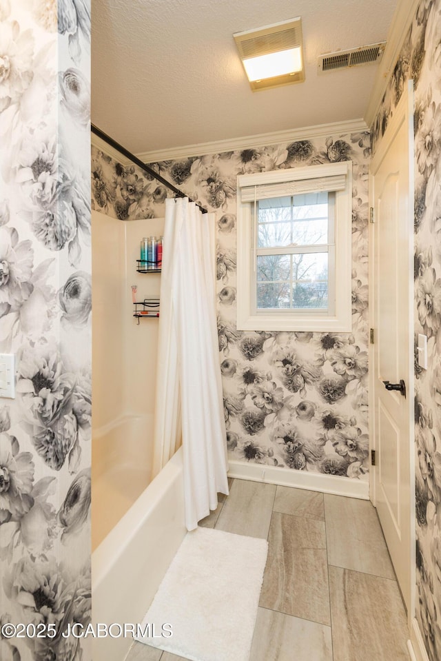 bathroom with crown molding, shower / bath combo with shower curtain, and a textured ceiling