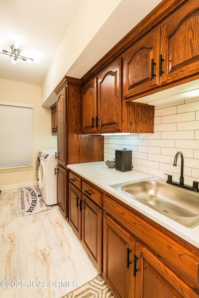 kitchen featuring washer and clothes dryer, sink, and decorative backsplash