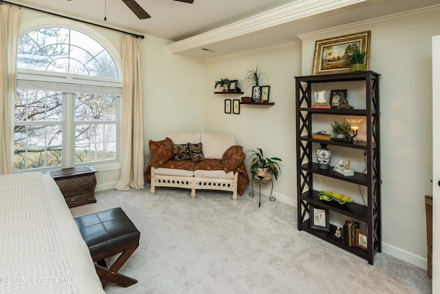 living area with ceiling fan, ornamental molding, and light carpet