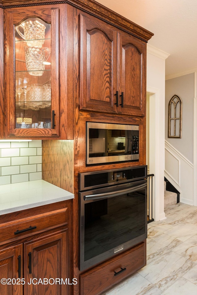 kitchen with backsplash, ornamental molding, and appliances with stainless steel finishes